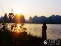 一名游客在广西宜州市怡人湖畔欣赏晚霞。（摄影：高东风）