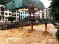 东兰：强降雨导致城内的九曲河水位暴涨，行人小心翼翼从桥上走过。（摄影：班伟）