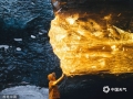 摄影师Sarah Bethea在冰岛冰洞拍摄到罕见一幕，太阳正好与山洞的入口排成一条直线，冰仿佛被点燃，看起来就像是琥珀。据悉，这一现象一年只有一两次。（SWNS/SWNS/版权图片 来源视觉中国）
