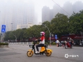 图为22日早晨，钦州市民在雾中骑车。（图/李斌喜）