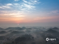 中国天气网讯 大年初二（13日）清晨，钦州市钦南区黄屋屯镇出现平流雾景观，村庄、大山、田野、河流等在雾气中若隐若现，如梦幻仙境一般。平流雾是由暖空气流移到较冷的陆地或水面时，下部冷却凝结形成。在适当的风向、风速下，平流雾会形成悬在半空中的“飘带雾”，附在水面和山间随风流动。（图文/李斌喜 ）