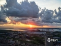 中国天气网讯 8月27日早晨，广西防城港市港口区东海湾上空，阳光冲破云层照耀大地，云朵也被染上了橘色光芒，十分美丽。（图文/曾海科）