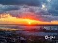 中国天气网讯 8月27日早晨，广西防城港市港口区东海湾上空，阳光冲破云层照耀大地，云朵也被染上了橘色光芒，十分美丽。（图文/曾海科）