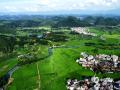 中国天气网广西站讯  6月23日，贺州富川瑶族自治县古城镇夏日盛景迷人。空中俯瞰，广袤田野如青绿绸缎，错落村舍似棋盘棋子，与山水相融，远处山峦朦胧。阳光晕染下，乡村尽显自然和谐之美，成为夏日里一道醉人的风景线 。（文/ 唐冬晓 董州   图/董州）