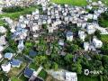 中国天气网广西站讯  6月23日，贺州富川瑶族自治县古城镇夏日盛景迷人。空中俯瞰，广袤田野如青绿绸缎，错落村舍似棋盘棋子，与山水相融，远处山峦朦胧。阳光晕染下，乡村尽显自然和谐之美，成为夏日里一道醉人的风景线 。（文/ 唐冬晓 董州  图/董州）