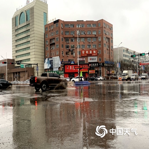 图为21日上午,营口大石桥市气温较高,降雨使马路上出现积水.